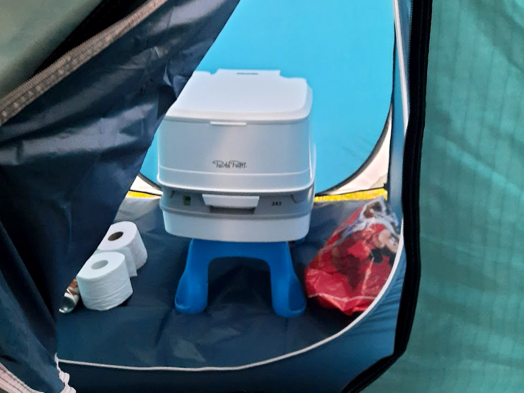 Een mobiel toilet in een tentje op de camping